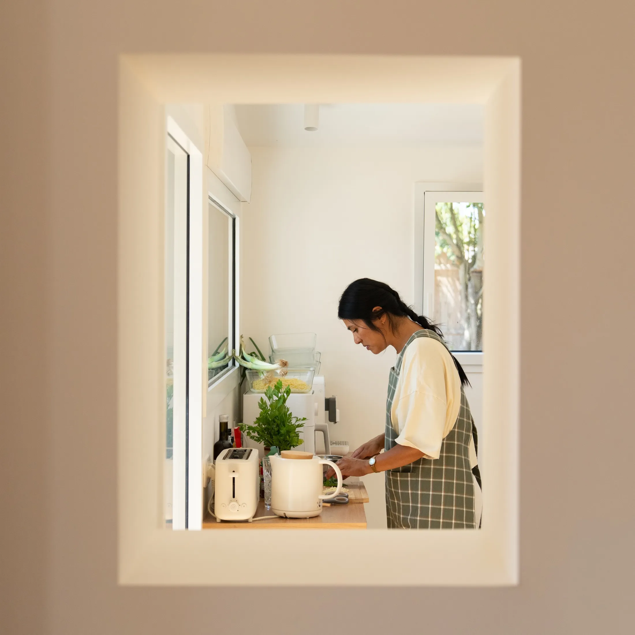 Christina en train de cuisiner, vue depuis l'entrée de sa cuisine lumineuse.