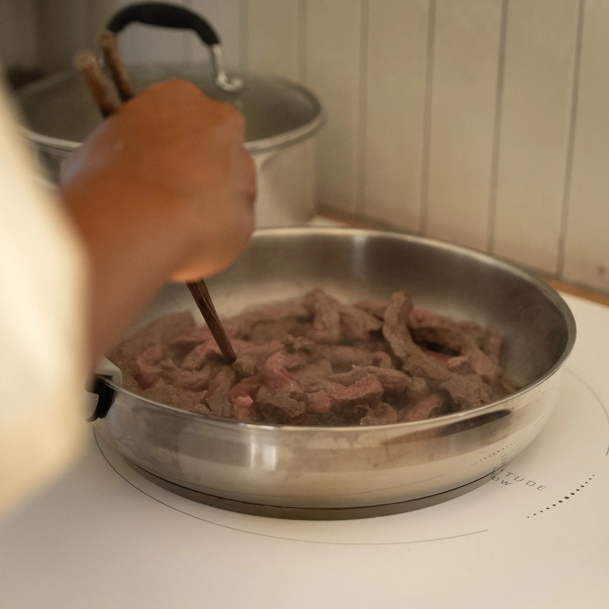 Lamelles de bœuf saisies à la poêle, geste précis aux baguettes.